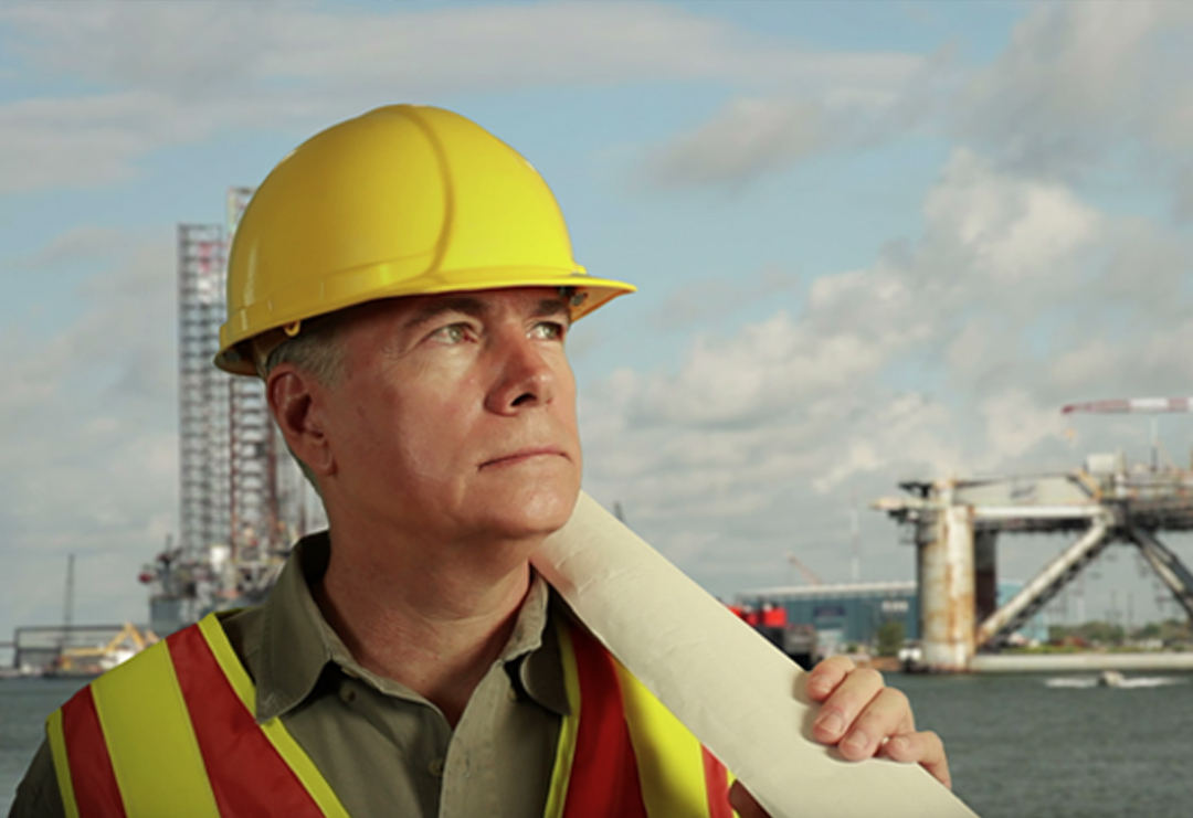 Construction worker with oil rig in the background